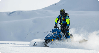 Person riding a snowmobile in snowy landscape representing snowmobile insurance coverage